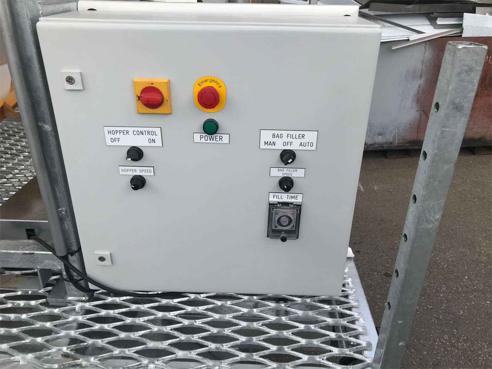 Can customise sandbagging trailers with any function, aesthetic, or feature. Photo of Control board with hopper control, hopper speed, bag filler control, & bag filler speed dials, fill time gauge, and big red emergency stop button with yellow emergency signage.