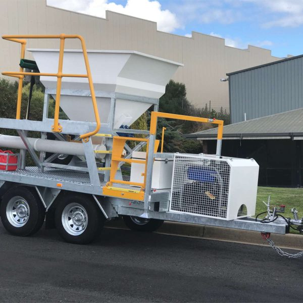 White Sandbagging Trailer with Safety Yellow Rails & Steps on road in front of green grass and buildings